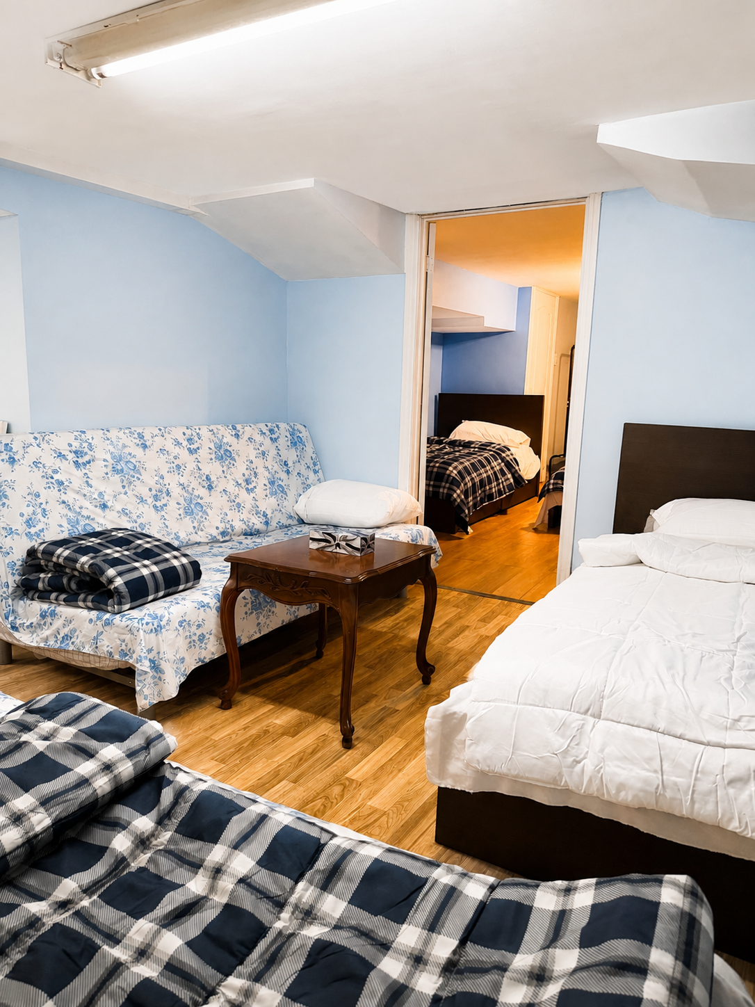 Shared accommodation bedroom featuring beds, floral seating area, coffee table, and adjoining sleeping space for SonoRAY course participants